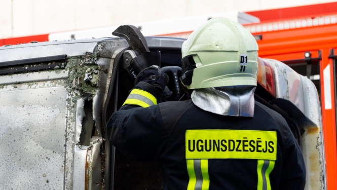 Ugunsdzēsējs ar instrumentu griež automašīnas jumtu