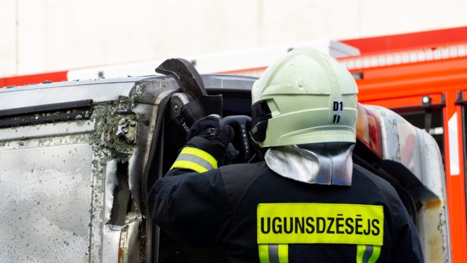 Ugunsdzēsējs ar instrumentu griež automašīnas jumtu