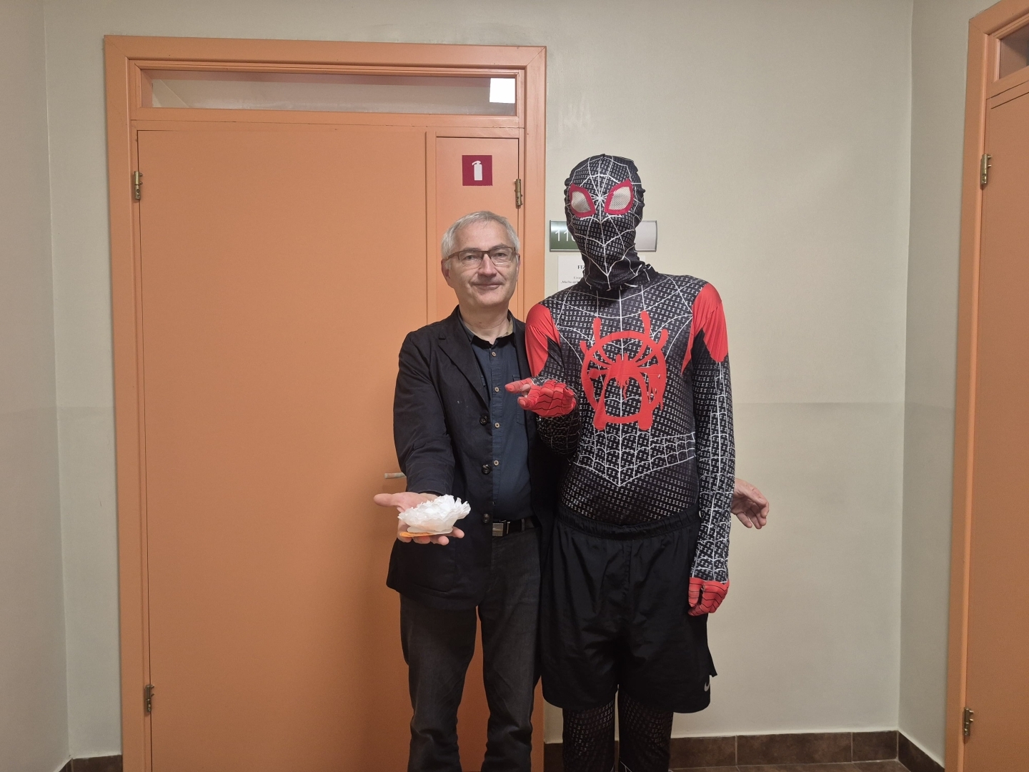 Pašvaldības pārstāvis cilvēka zirnekļa kostīmā kopā ar pedagogu
