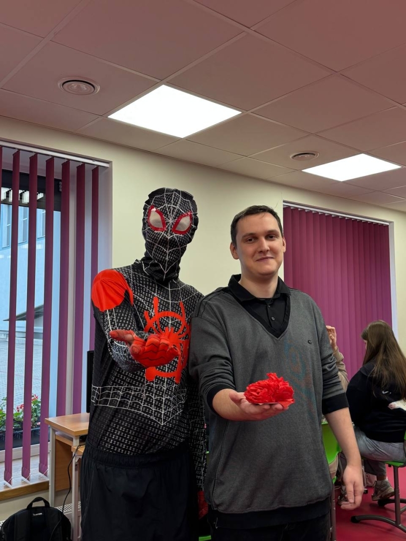 Pašvaldības pārstāvis cilvēka zirnekļa kostīmā kopā ar pedagogu