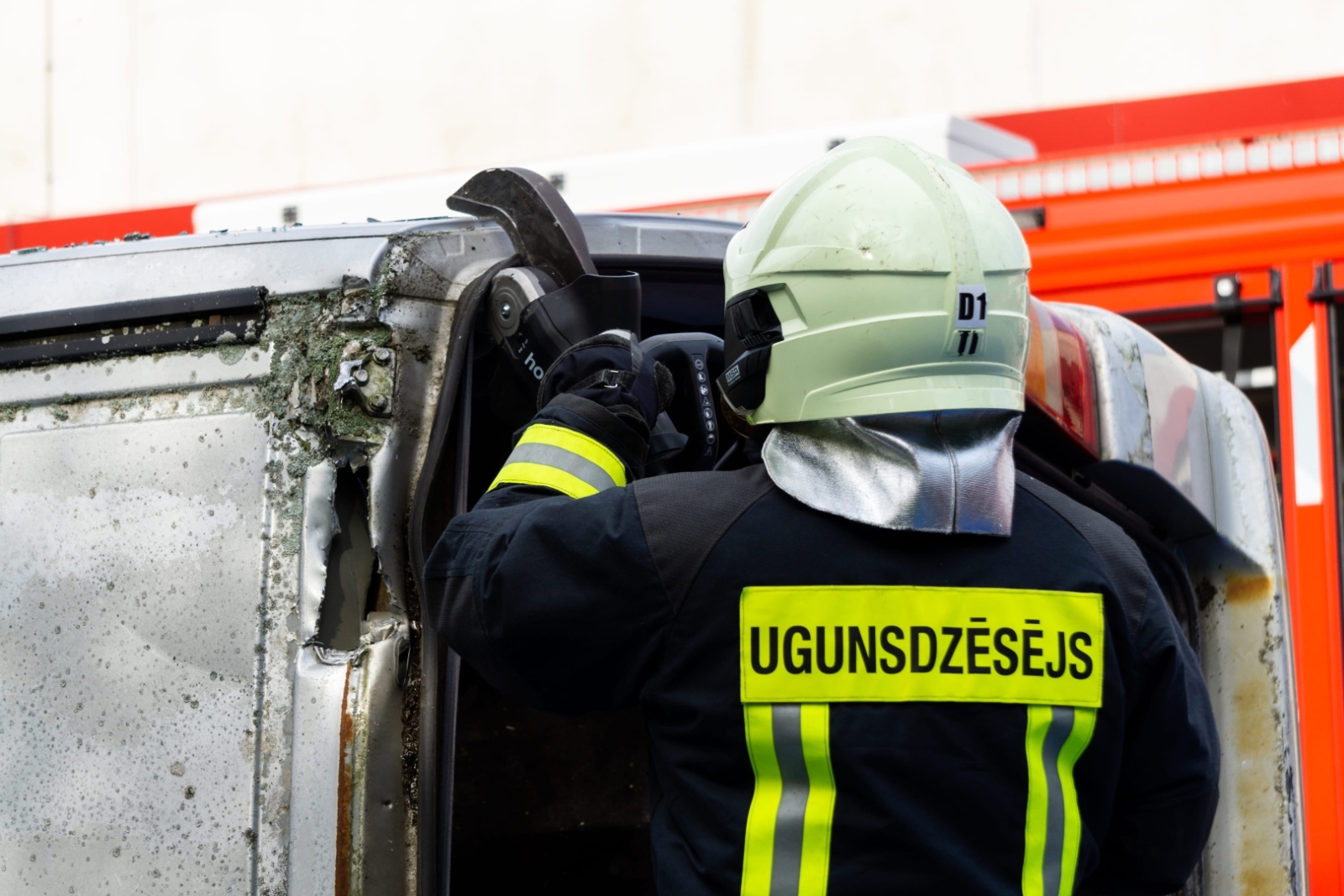 Ugunsdzēsējs ar instrumentu griež automašīnas jumtu
