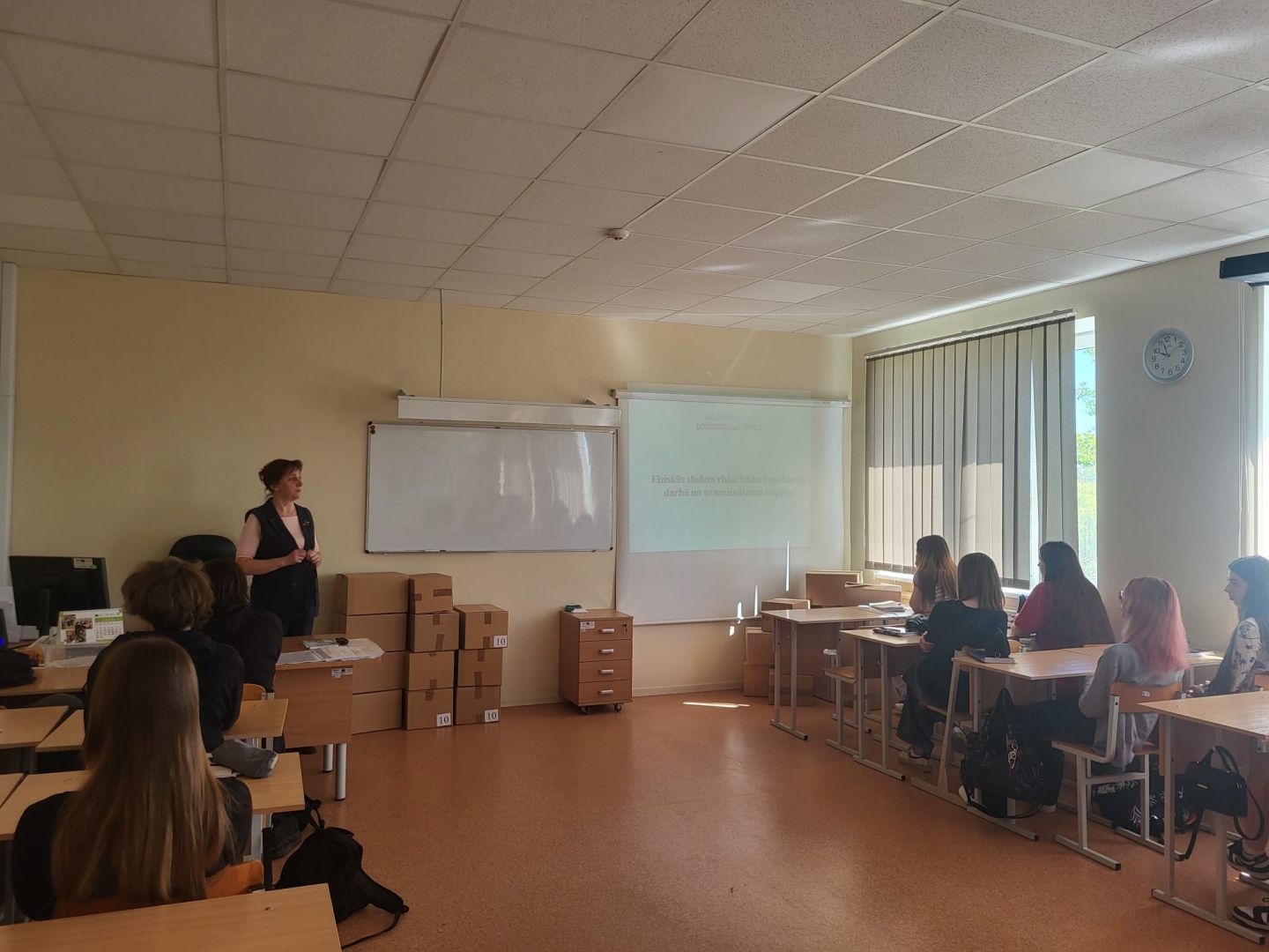 Pedagoģe iepazīstina izglītojamos ar fiziskās slodzes riska faktoriem noliktavas darbā