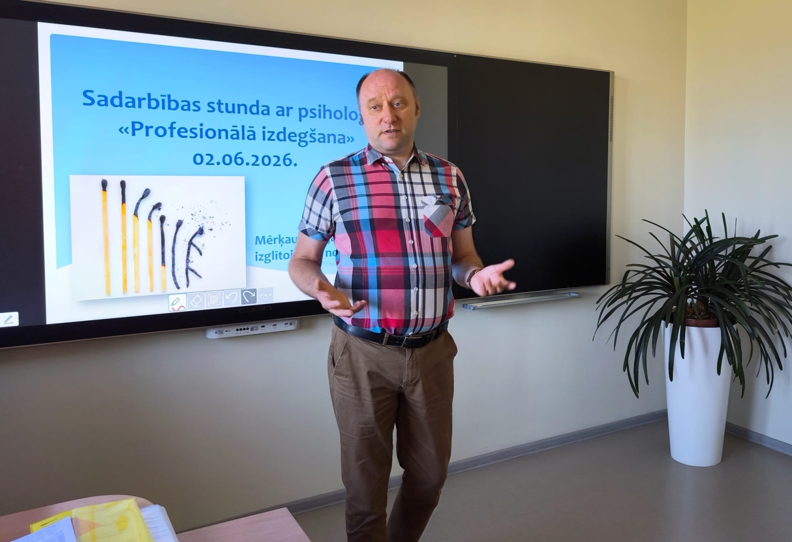 Skolotājs vada stundu klases priekšā pie interaktīvās tāfeles