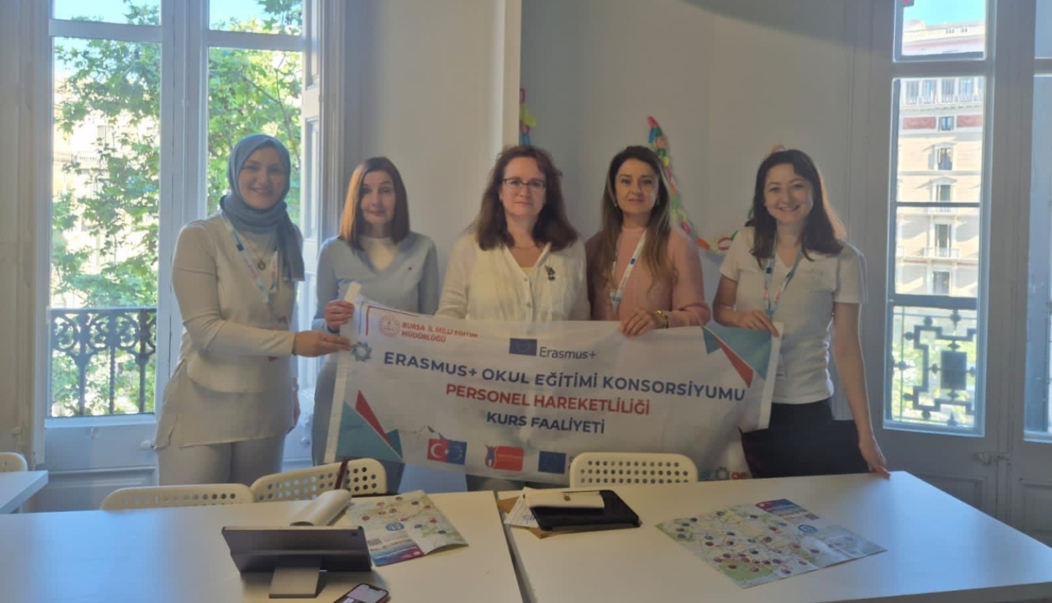 Piecas Erasmus+ kursu dalībnieces pozē grupas foto ar projekta baneri