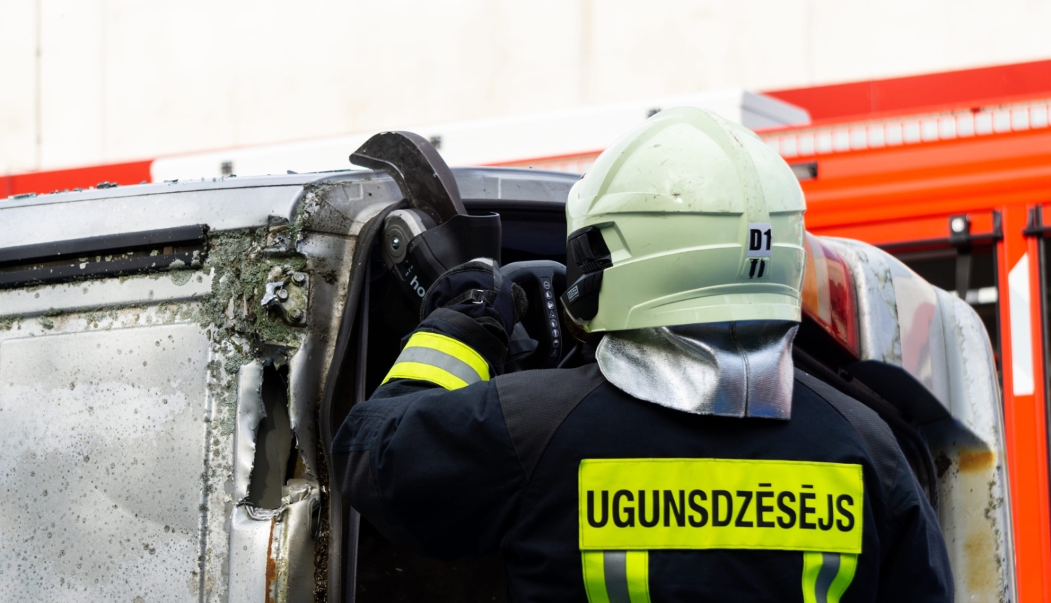 Ugunsdzēsējs ar instrumentu griež automašīnas jumtu