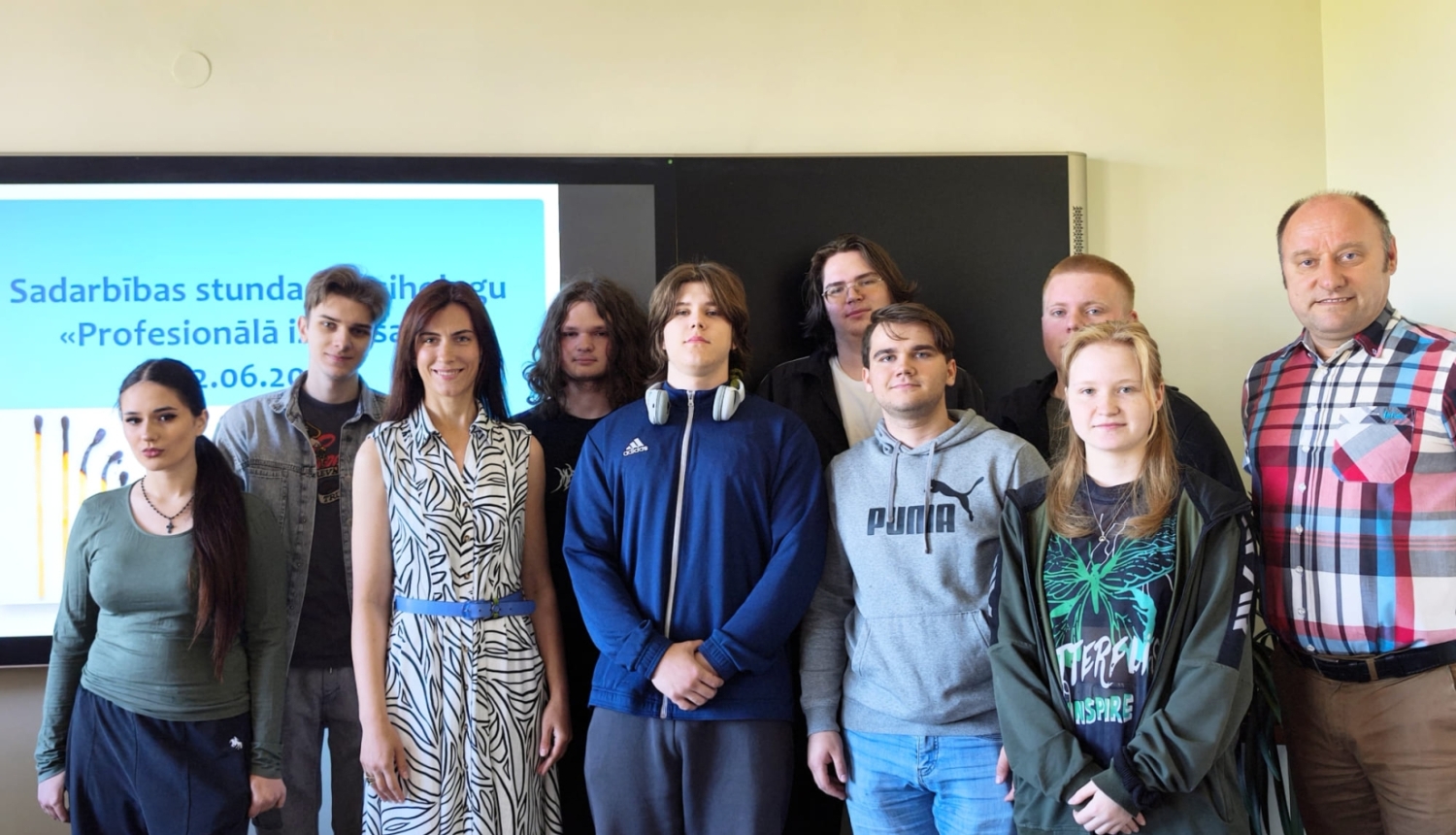 Kopbildē redzami izglītojamie un pedagogi pie interaktīvās tāfeles