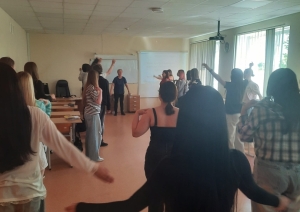 Izglītojamie piedalās iesildīšanas vingrinājumos sadarbības stundā par drošu kravu pārvietošanu noliktavā
