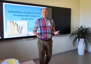 Skolotājs vada stundu klases priekšā pie interaktīvās tāfeles
